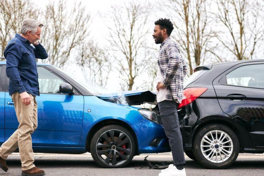 Two men inspect a blue car, discussing a rear