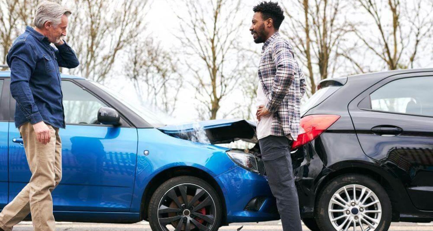 Two men inspect a blue car, discussing a rear